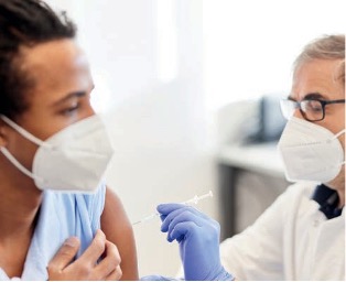 Chefarzt Dr. med. Klaus Rainer Fuchs bei der Impfung eines jungen Patienten.